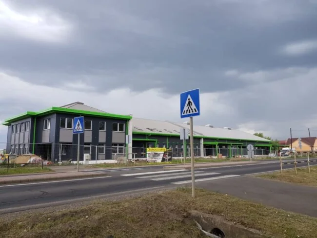 Gewerbehallen mit grünen Akzentstreifen an einer Straße